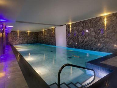 An indoor swimming pool with tiled walls and steps leading into the water at The Blithe Hare in Troutbeck Bridge