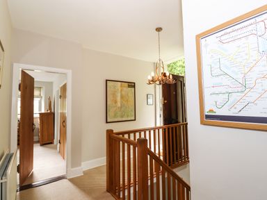 A hallway with wooden railing and open doors showing a room with furniture at The Mews in Ambleside