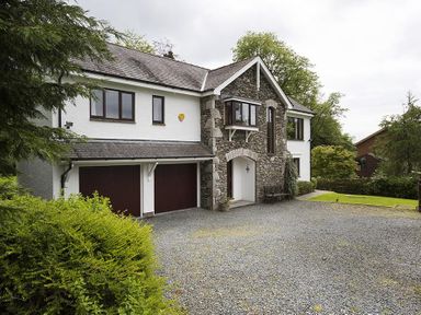A two-story house with a stone and white exterior and a gravel driveway at March House in Windermere