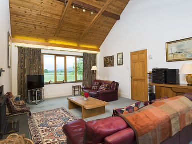 A living room with leather sofas a wooden coffee table a patterned rug and a large window at March House in Windermere