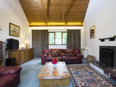 A living room with red leather sofas a wooden coffee table a patterned rug and a fireplace at March House in Windermere