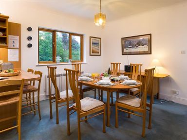 A dining room with a wooden table set for six and wooden chairs at March House in Windermere