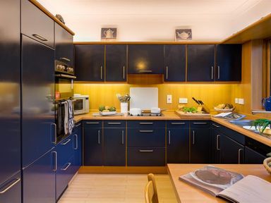 A kitchen with blue cabinets wooden countertops an oven a microwave utensils and an open cookbook at March House Windermere