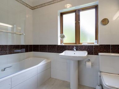 A bathroom with a bathtub shower sink toilet and window at March House in Windermere