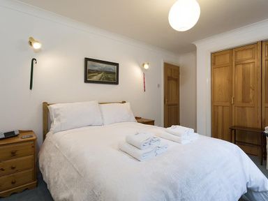A bedroom with a double bed with white bedding and towels folded on top at March House in Windermere