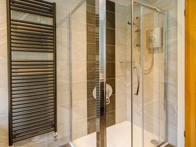 A bathroom with a glass shower enclosure and a black towel radiator at March House in Windermere