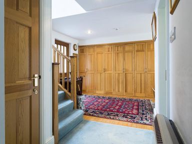 A hallway with wooden doors a staircase with carpet and a patterned rug at March House in Windermere