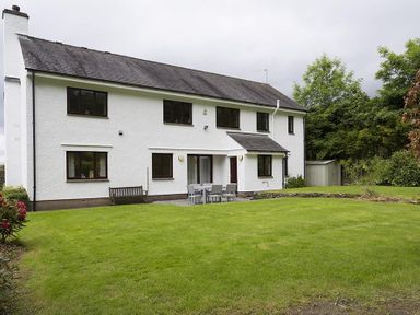 A white two-story house with a garden and outdoor seating at March House in Windermere