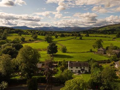 A countryside landscape with green fields trees and houses at March House in Windermere
