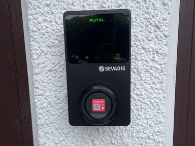 A black SEVADIS Autel device mounted on a white textured wall between two brown frames