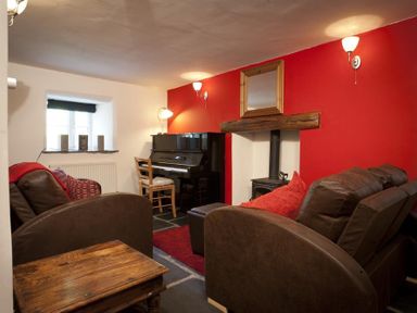 A living room with a piano two brown sofas a wooden side table and a fireplace at Wythebank in Langdale