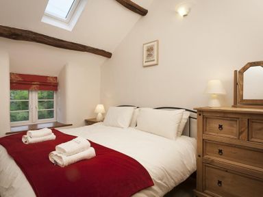 A bedroom with a double bed white linens wooden dresser and window with red blinds at Wythebank in Langdale