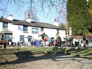 An outdoor seating area with people at tables outside a white building with multiple windows at Wythebank in Langdale