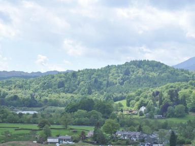 A rural landscape with houses fields and forested hills at Wythebank in Langdale