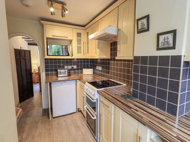 A kitchen with cabinets, stove and sink at Smithy Cottage at Bowland Bridge in Bowness