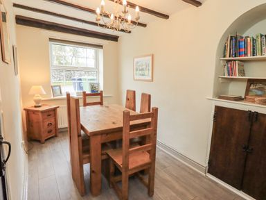 A dining room with a wooden table and chairs at Smithy Cottage at Bowland Bridge Bowness