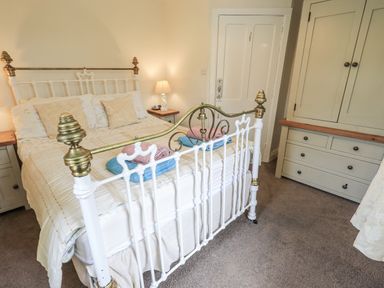 A bedroom with a bed and wardrobe at Smithy Cottage at Bowland Bridge in Bowness