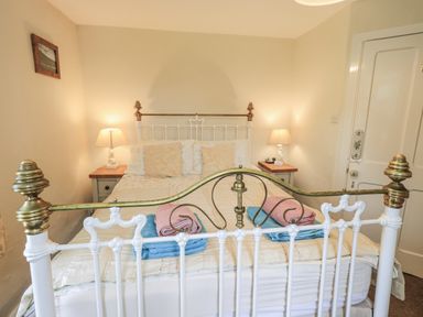 A bedroom with a bed and bedside table at Smithy Cottage at Bowland Bridge Bowness