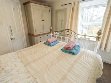 A bedroom with a bed and wardrobe at Smithy Cottage at Bowland Bridge in Bowness