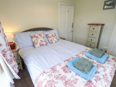 A bedroom with a bed and dresser at Smithy Cottage at Bowland Bridge