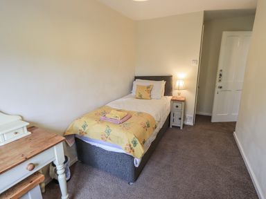 A bedroom with a single bed and nightstand at Smithy Cottage at Bowland Bridge, Bowness