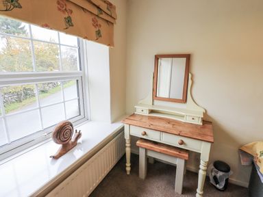 A vanity table with a mirror and a snail sculpture in a bedroom at Smithy Cottage at Bowland Bridge Bowness