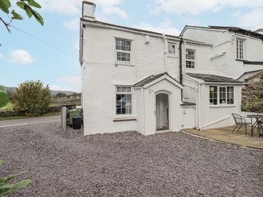A house exterior with a front yard and seating area at Smithy Cottage at Bowland Bridge in Bowness