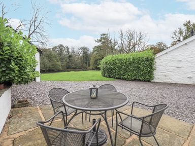 An outdoor seating area with a table and chairs at Smithy Cottage at Bowland Bridge Bowness