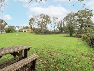 A garden with a table and trees at Smithy Cottage at Bowland Bridge Bowness