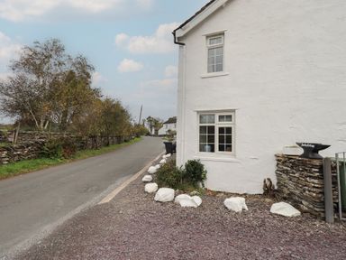An exterior view showing a house and road at Smithy Cottage at Bowland Bridge, Bowness