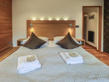 A bedroom with a double bed brown pillows and folded towels on the bed at Idle Mill 1 in Ambleside