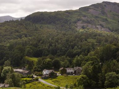 A small village surrounded by dense forest and hills with a road passing through at Le Chalet in Elterwater