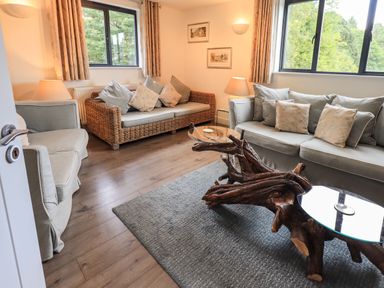 A living room with sofas and armchairs and a wooden coffee table with glass tops at Le Chalet in Elterwater