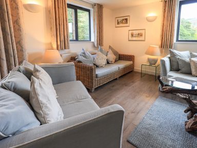 A living room with sofas cushions lamps and framed pictures at Le Chalet in Elterwater