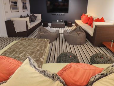 A living room with two sofas with cushions bean bags and a wall mounted television at Le Chalet in Elterwater