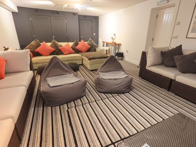A living room with striped carpet two bean bag chairs and sofas with cushions at Le Chalet in Elterwater