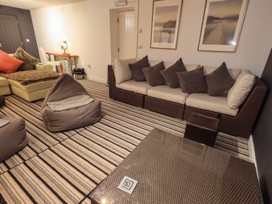 A living room with a striped carpet brown bean bags and framed pictures on the wall at Le Chalet in Elterwater