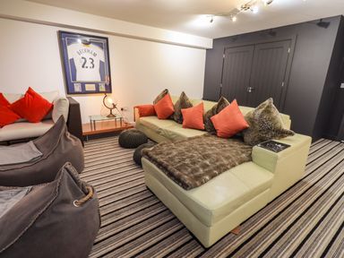 A living room with a striped carpet sofas bean bags cushions and a framed sports jersey on the wall at Le Chalet in Elterwater