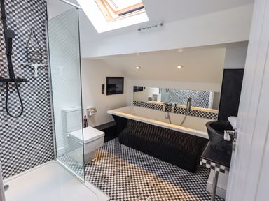 A bathroom with a shower, toilet, bathtub, sink, and skylight at Le Chalet in Elterwater