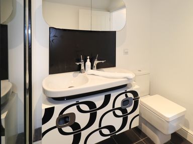 A bathroom with a white double sink and black and white patterned cabinet next to a white toilet at Le Chalet in Elterwater