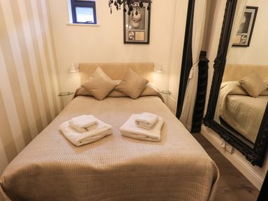 A bedroom with a bed and two pillows two sets of towels on the bed a large mirror and a small window at Le Chalet in Elterwater