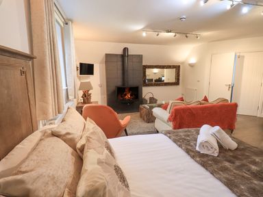 A bedroom with a bed towels and a fireplace a sofa and an armchair at Le Chalet in Elterwater
