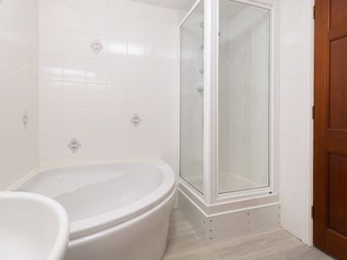 A bathroom with a bathtub shower enclosure and wooden door at High Lake in Bowness