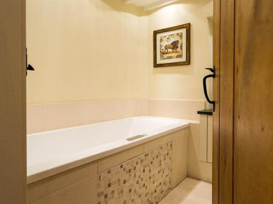 A bathroom with a bathtub a framed picture of a lion on the wall and a wooden door at Ivy Cottage in Ambleside