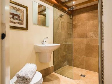 A bathroom with a walk-in shower sink framed artwork and towels at Ivy Cottage in Ambleside