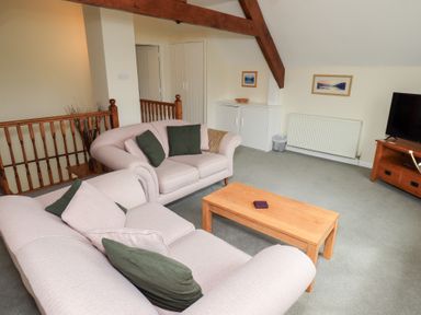A living room with two sofas green cushions a wooden coffee table a TV on a wooden stand and framed pictures on the wall at The Old Chapel in Crook