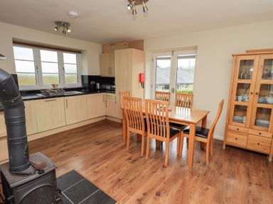 A kitchen and dining area with wooden cabinets dining table six chairs wood stove and glass cabinet at The Old Chapel in Crook