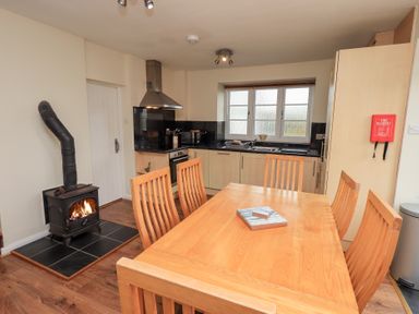 A kitchen with a wooden dining table and chairs a wood stove and appliances at The Old Chapel in Crook