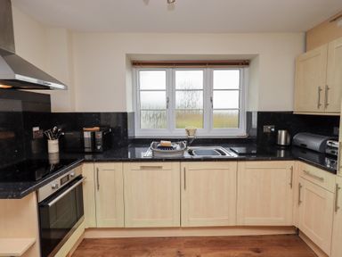 A kitchen with wooden cabinets black countertops a double sink microwave oven and utensils at The Old Chapel in Crook