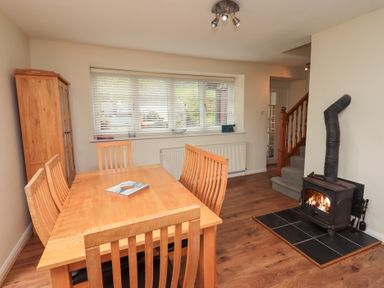A dining room with wooden table and chairs a wood stove and staircase at The Old Chapel in Crook